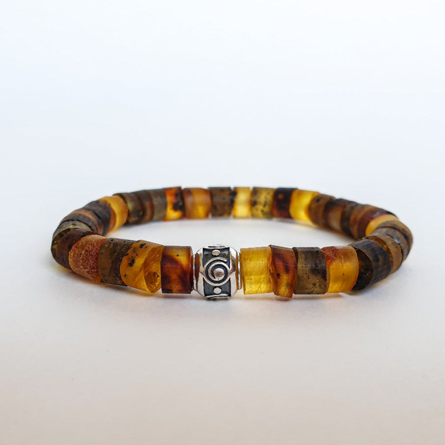 A bracelet made of natural amber beads with a silver 925 accent bead featuring a spiral design, displayed against a white background.