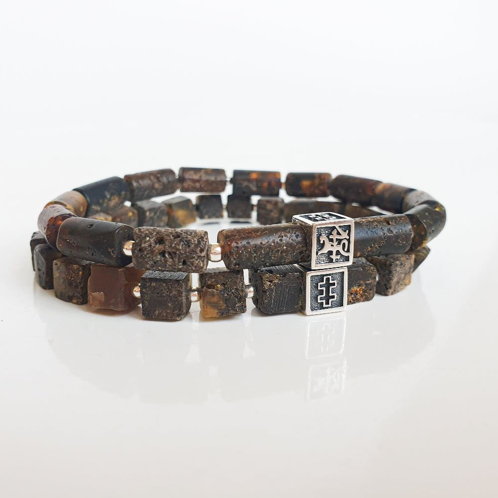 Stack of dark beaded bracelets with a silver clasp on a white background