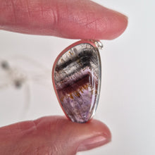 Load image into Gallery viewer, Teardrop-shaped purple stone pendant held between fingers against a white background