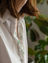 Load image into Gallery viewer, Person wearing a white shirt with a green beaded necklace, blurred background