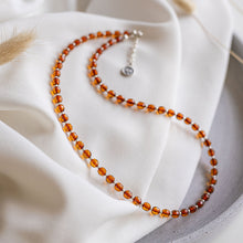 Load image into Gallery viewer, Necklace with amber beads on a white fabric background