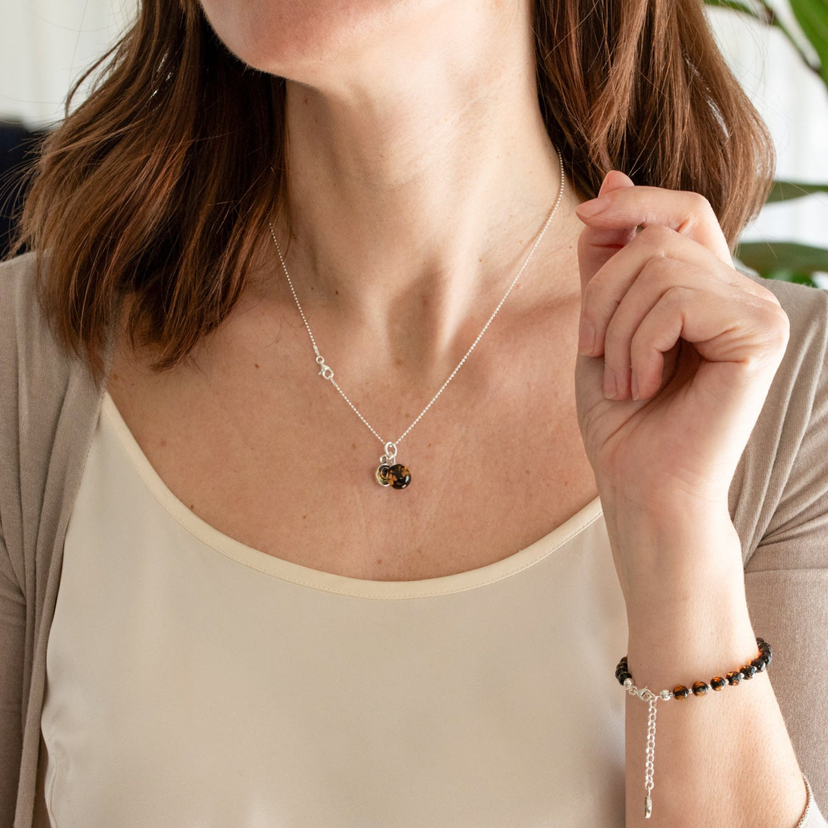 Woman wearing a necklace and bracelet with a neutral background