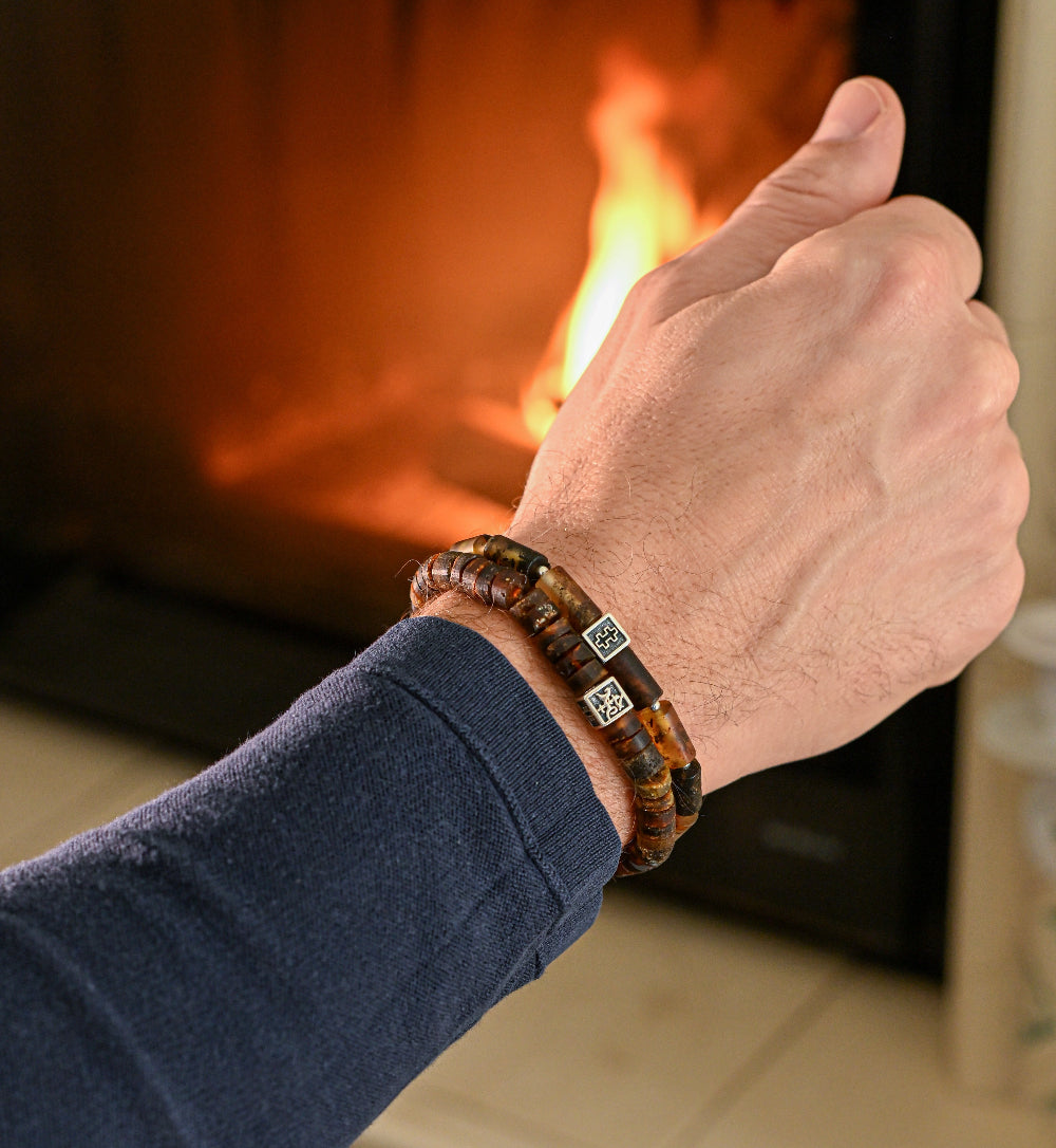 Hand wearing a bracelet with a fireplace in the background