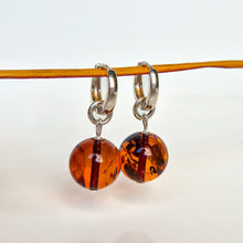 Load image into Gallery viewer, Pair of amber-colored hoop earrings on a thin rod against a white background