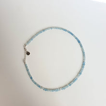 Load image into Gallery viewer, A beaded necklace with light blue aquamarine stones and a handmade silver medallion with a spiral design.